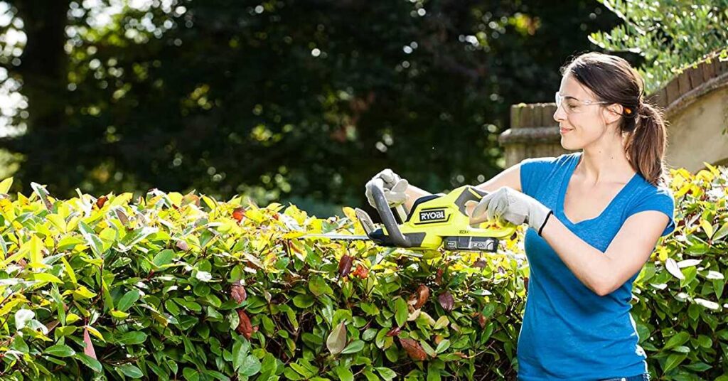 jeune femme avec taille haie ryobi 18v dans son jardin